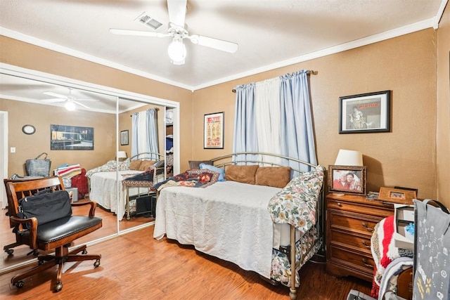 bedroom with hardwood / wood-style floors, ceiling fan, ornamental molding, and a closet