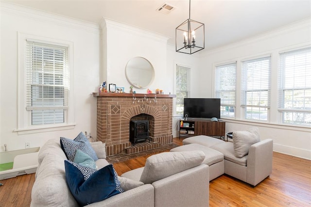 living room with hardwood / wood-style flooring, a notable chandelier, a wood stove, and ornamental molding