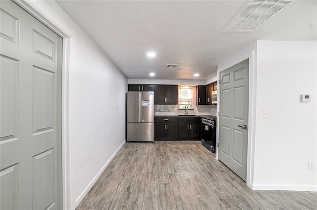 kitchen featuring dark brown cabinetry, sink, appliances with stainless steel finishes, and light hardwood / wood-style flooring