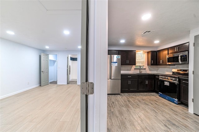 kitchen with dark brown cabinets, stainless steel appliances, light hardwood / wood-style floors, and sink