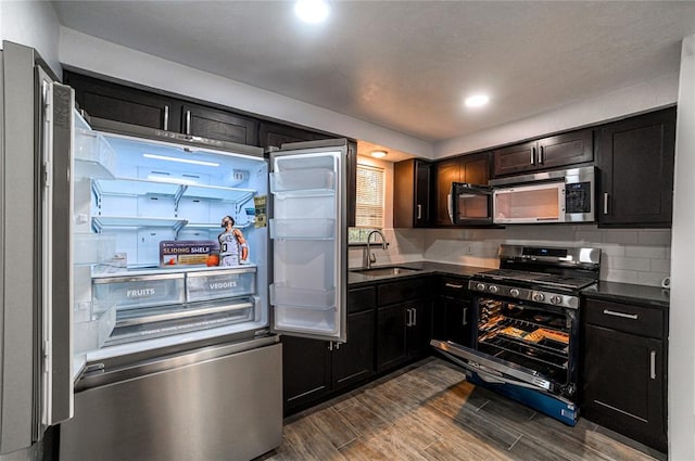 kitchen featuring dark hardwood / wood-style flooring, sink, stainless steel appliances, and tasteful backsplash