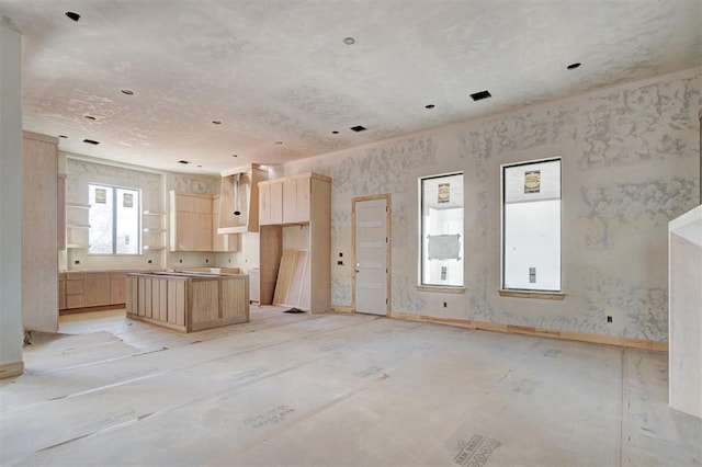 kitchen with open floor plan, light brown cabinetry, open shelves, and a center island