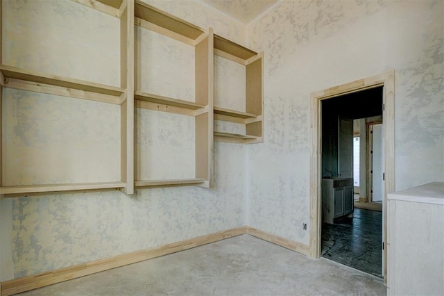 unfurnished room featuring concrete flooring, baseboards, and wallpapered walls