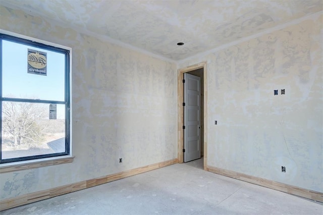 empty room featuring baseboards and crown molding