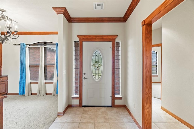 entrance foyer featuring a wealth of natural light, crown molding, light carpet, and a notable chandelier