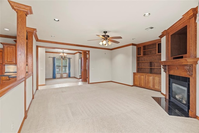 unfurnished living room featuring ceiling fan with notable chandelier, light colored carpet, crown molding, and a tiled fireplace