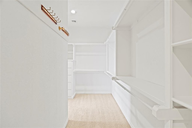 walk in closet with light colored carpet