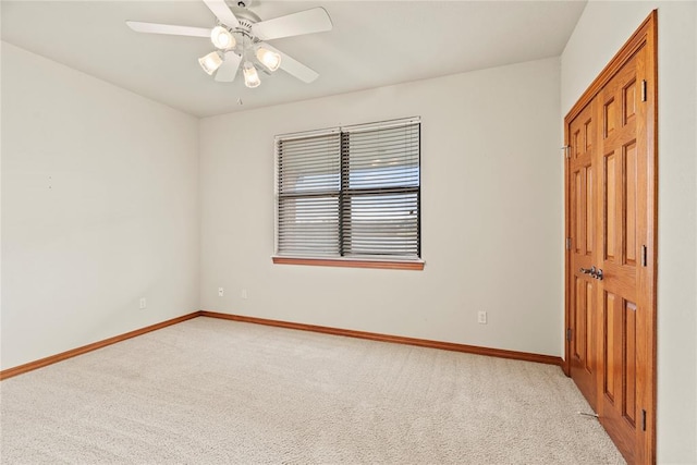 spare room with ceiling fan and light colored carpet