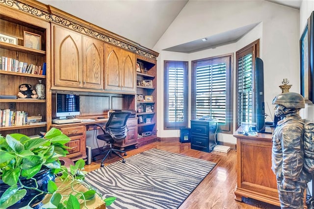 office featuring hardwood / wood-style flooring, lofted ceiling, and built in desk