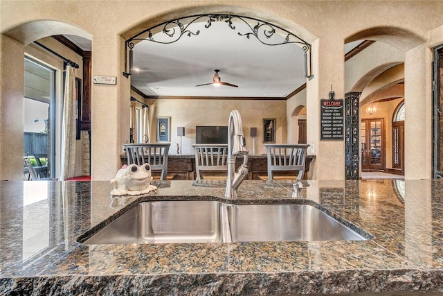 kitchen with dark stone countertops, ceiling fan, sink, and ornamental molding