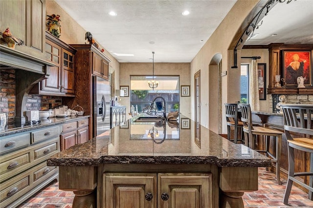 kitchen featuring stainless steel built in refrigerator, pendant lighting, a spacious island, and sink