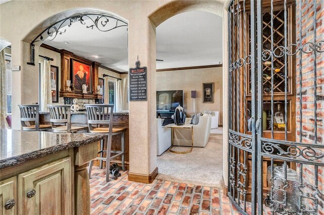 kitchen featuring light colored carpet, dark stone counters, and ornamental molding