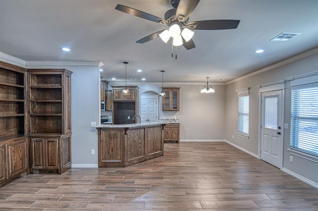 kitchen featuring ceiling fan with notable chandelier, dark hardwood / wood-style floors, crown molding, and decorative light fixtures