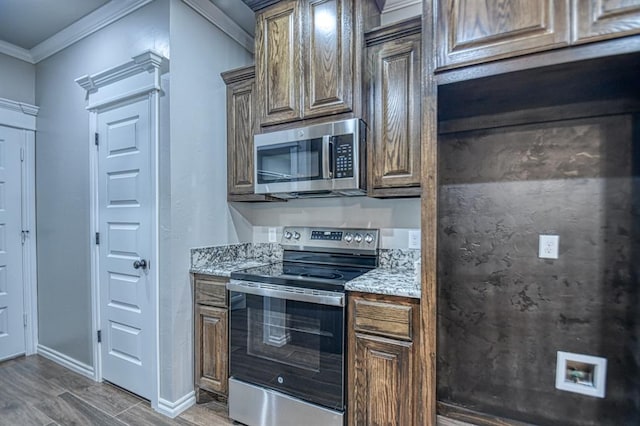 kitchen with light stone counters, ornamental molding, dark wood-type flooring, and appliances with stainless steel finishes