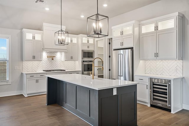 kitchen featuring stainless steel appliances, white cabinets, dark hardwood / wood-style floors, wine cooler, and an island with sink