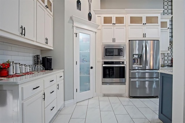 kitchen with white cabinets, backsplash, stainless steel appliances, and light tile patterned flooring