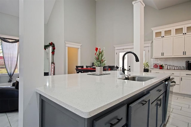 kitchen featuring gray cabinets, sink, white cabinetry, and an island with sink