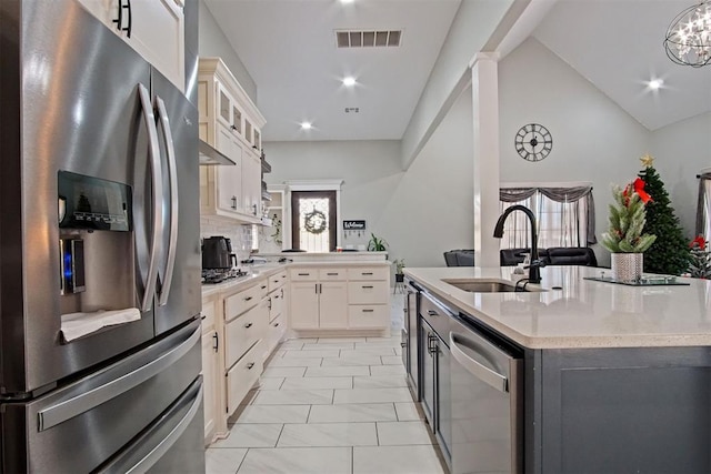 kitchen with white cabinets, sink, appliances with stainless steel finishes, and vaulted ceiling