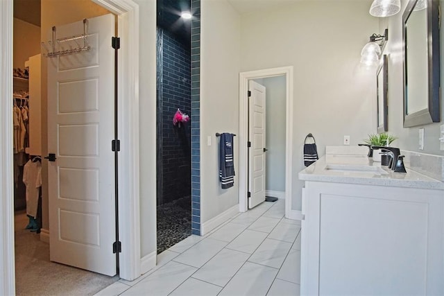 bathroom featuring tile patterned flooring, a tile shower, and vanity