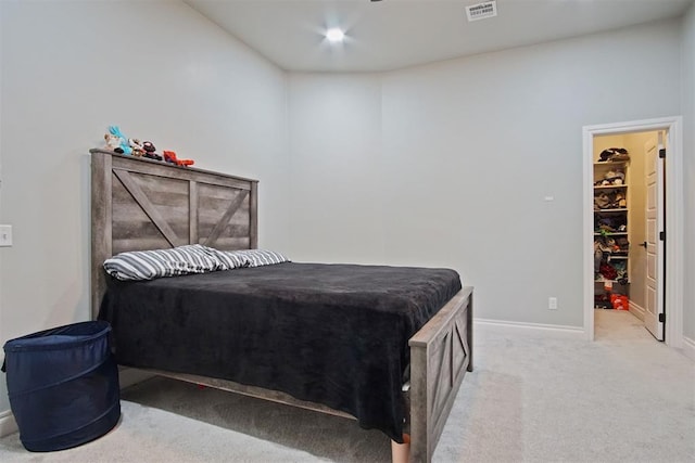 bedroom featuring a walk in closet and light carpet