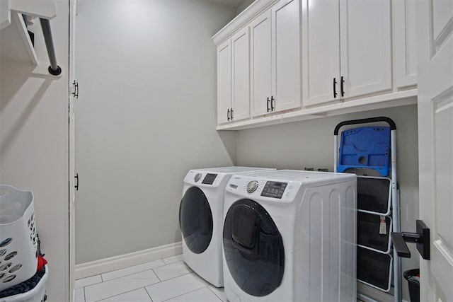 laundry area with washer and clothes dryer, light tile patterned flooring, and cabinets