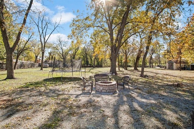 view of yard featuring a trampoline, a shed, and an outdoor fire pit