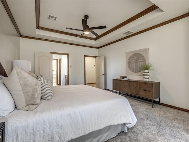 carpeted bedroom featuring ceiling fan, a raised ceiling, ornamental molding, and ensuite bath