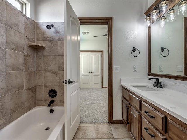 bathroom featuring tile patterned flooring, tiled shower / bath combo, and vanity