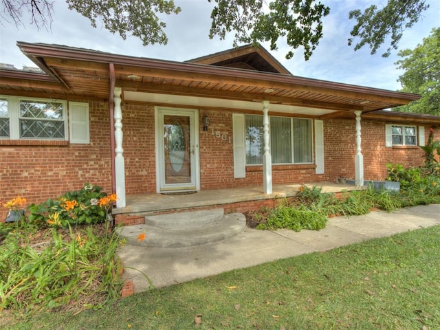 1501 S Avery Ave, Midwest City, OK 73130 - doorway to property featuring a porch and brick siding