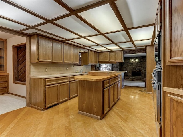1501 S Avery Ave, Midwest City, OK 73130 - kitchen featuring wood counters, a stone fireplace, a kitchen island, and brown cabinets