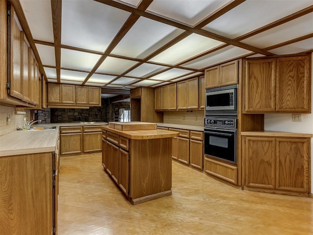 1501 S Avery Ave, Midwest City, OK 73130 - kitchen with oven, stainless steel microwave, a center island, and brown cabinets