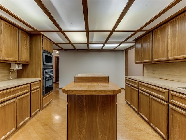 1501 S Avery Ave, Midwest City, OK 73130 - kitchen featuring oven, wood counters, stainless steel microwave, a kitchen island, and brown cabinets