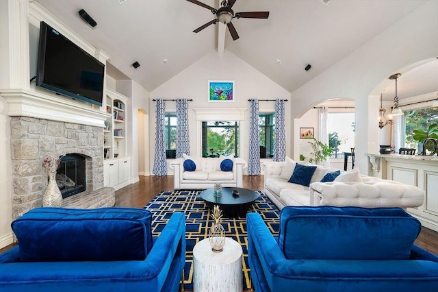 living room with ceiling fan, a stone fireplace, dark hardwood / wood-style flooring, high vaulted ceiling, and built in features