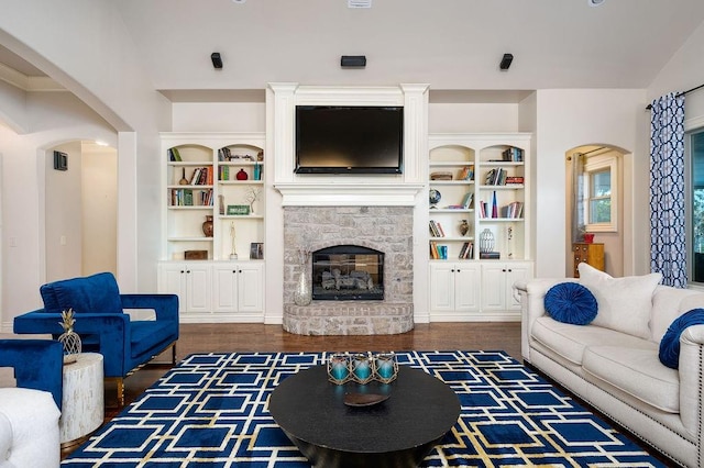 living room with a stone fireplace and dark wood-type flooring