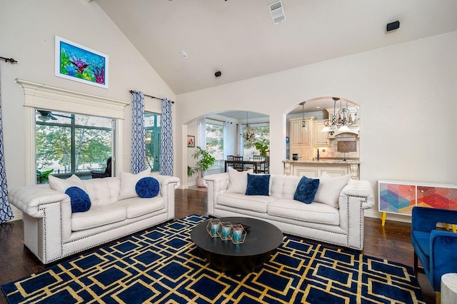 living room with dark hardwood / wood-style floors, high vaulted ceiling, and a notable chandelier