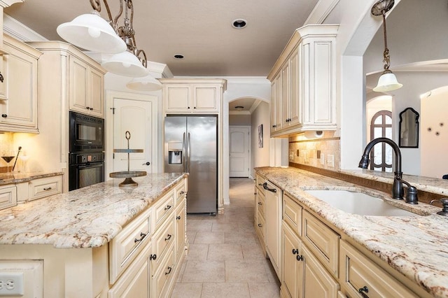 kitchen featuring sink, tasteful backsplash, light stone counters, decorative light fixtures, and black appliances