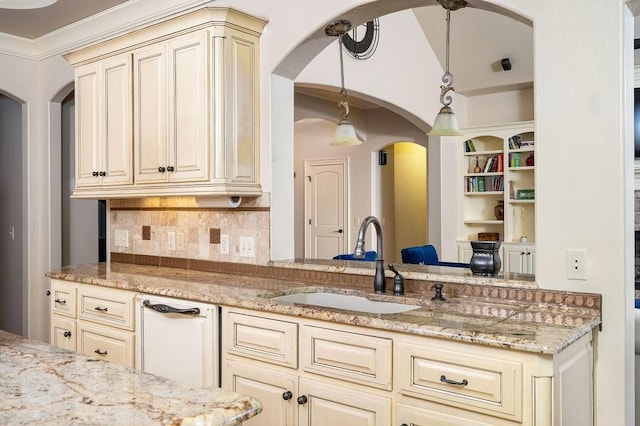 kitchen with pendant lighting, light stone counters, sink, and cream cabinets