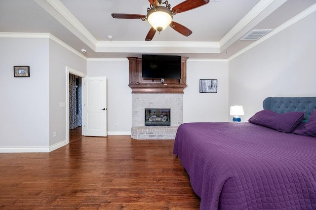 bedroom featuring crown molding, ceiling fan, dark wood-type flooring, and a brick fireplace