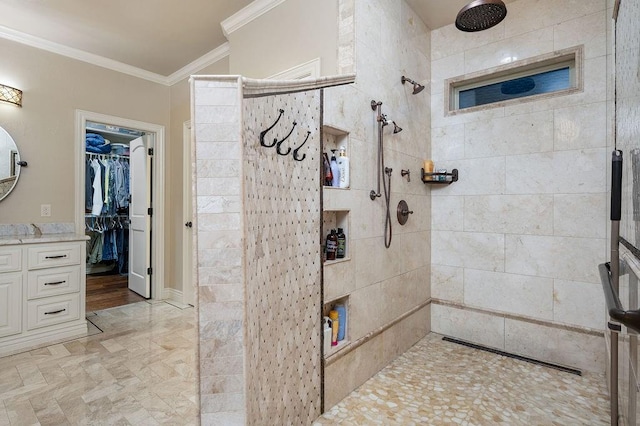 bathroom featuring a tile shower, vanity, and ornamental molding