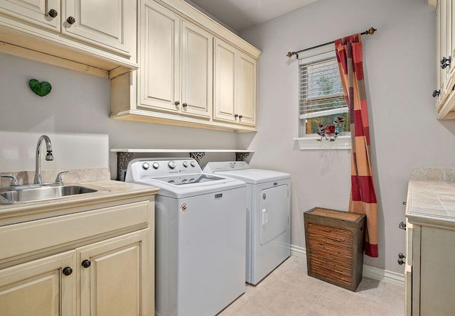 laundry room featuring washer and clothes dryer, sink, light tile patterned flooring, and cabinets