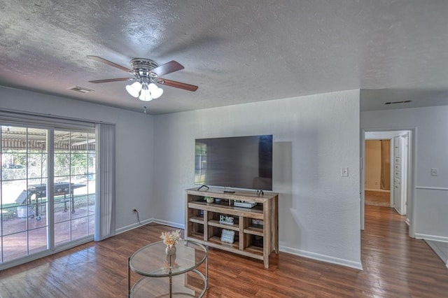 living room with a textured ceiling, dark hardwood / wood-style flooring, and ceiling fan