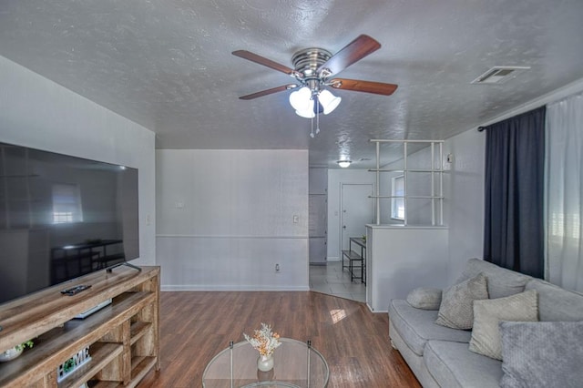 living room featuring ceiling fan, dark hardwood / wood-style flooring, and a textured ceiling