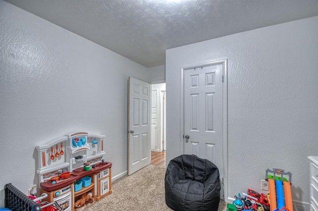 recreation room featuring light carpet and a textured ceiling