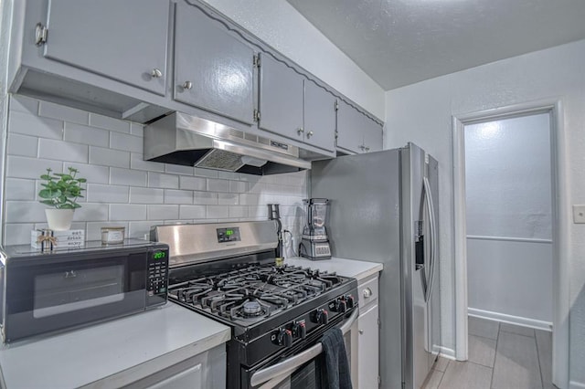 kitchen with gray cabinetry, decorative backsplash, light tile patterned flooring, and appliances with stainless steel finishes