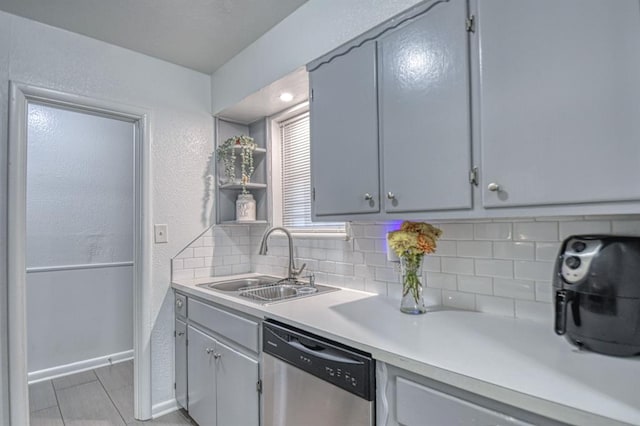 kitchen featuring backsplash, gray cabinets, sink, and stainless steel dishwasher