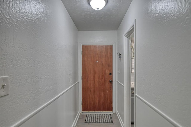 doorway to outside with a textured ceiling