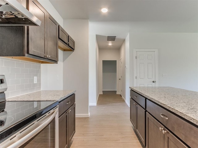 kitchen featuring dark brown cabinets, extractor fan, stainless steel range with electric stovetop, and light hardwood / wood-style floors