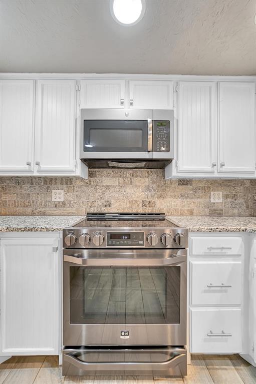 kitchen featuring light stone counters, white cabinetry, stainless steel appliances, and tasteful backsplash