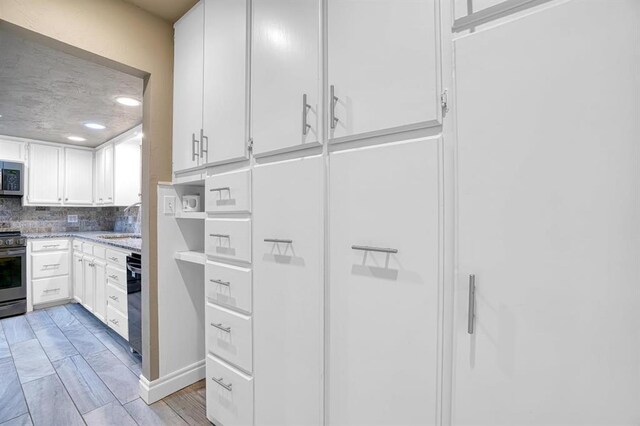 kitchen featuring decorative backsplash, appliances with stainless steel finishes, light stone countertops, sink, and white cabinetry