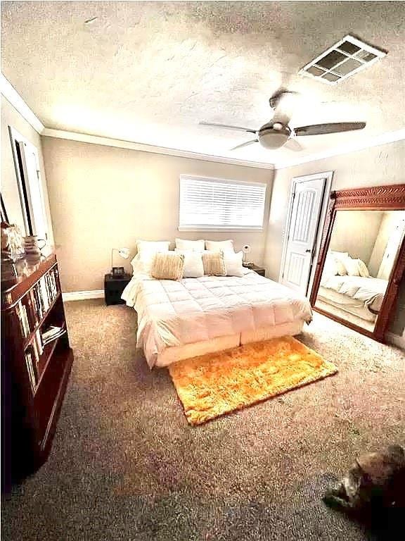 bedroom featuring ceiling fan, dark carpet, ornamental molding, and a textured ceiling